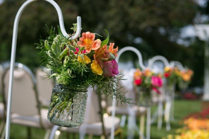 A row of mason jars with flowers in them.