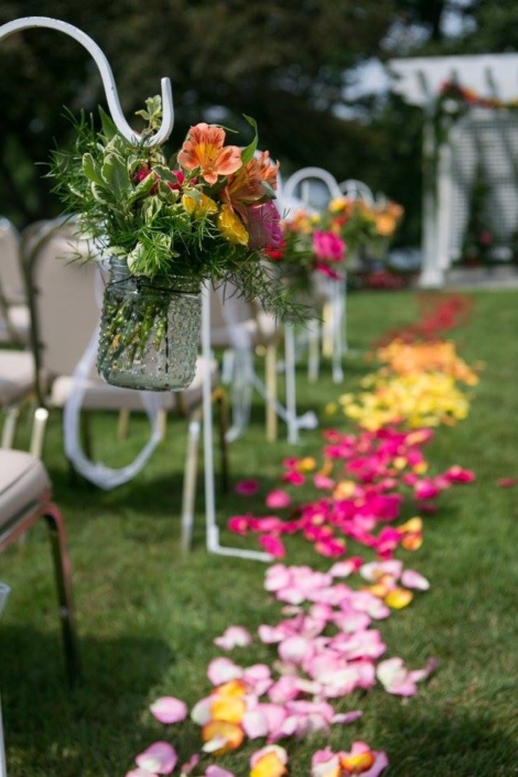 An outdoor wedding with colorful petals on the lawn.