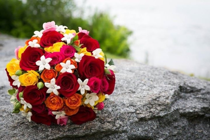 A bouquet of colorful roses sits on top of a rock.