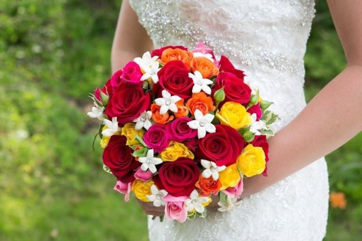 A bride holds a bouquet of colorful roses.