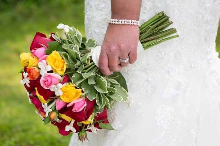 A bride is holding a bouquet of colorful flowers.