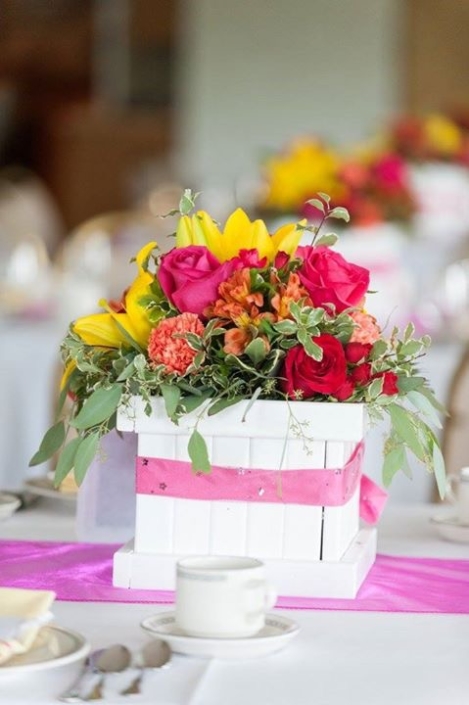 A table setting with colorful flowers and a pink runner.