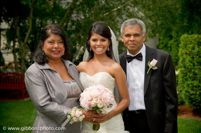 A bride and her parents pose for a photo.