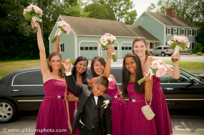 A group of bridesmaids holding bouquets in front of a limo.