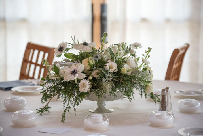 A centerpiece with white flowers on a table.