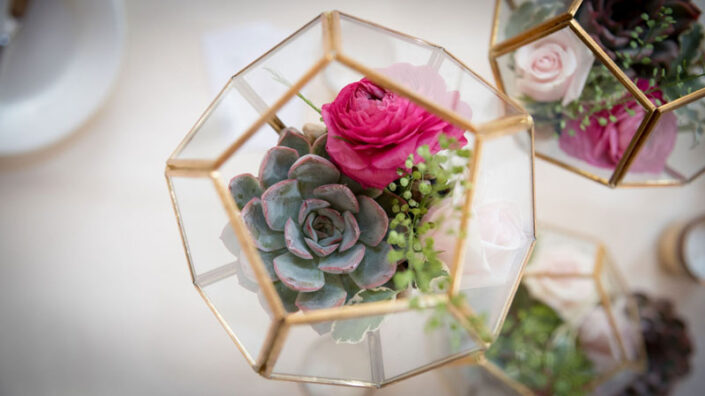 A glass vase filled with succulents and roses on a table.