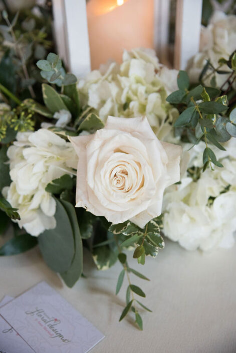 An arrangement of white roses and greenery on a table.