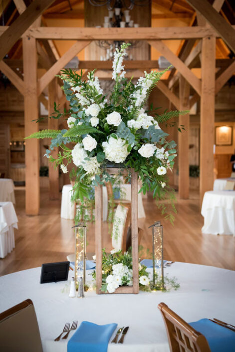A wedding reception with a wooden table and white flowers.