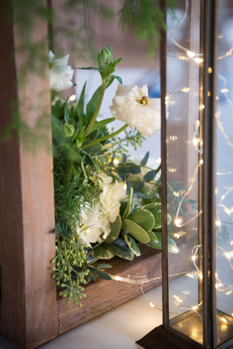 An arrangement of flowers and greenery in a wooden lantern.