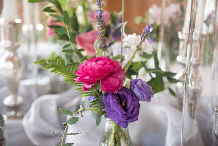 Purple and pink flowers in glass vases on a table.
