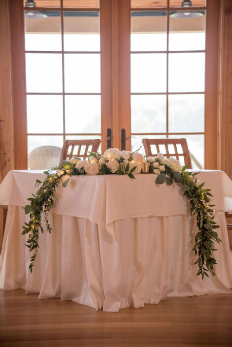 A white table with greenery and flowers on it.