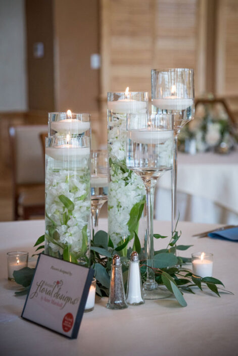 A centerpiece with candles and greenery on a table.
