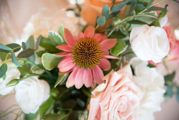A close up of a flower arrangement with peach and white flowers.