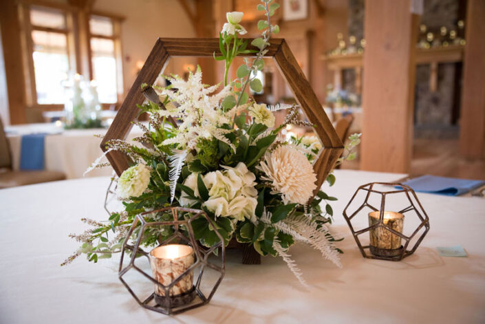 A table with a floral arrangement and candles on it.