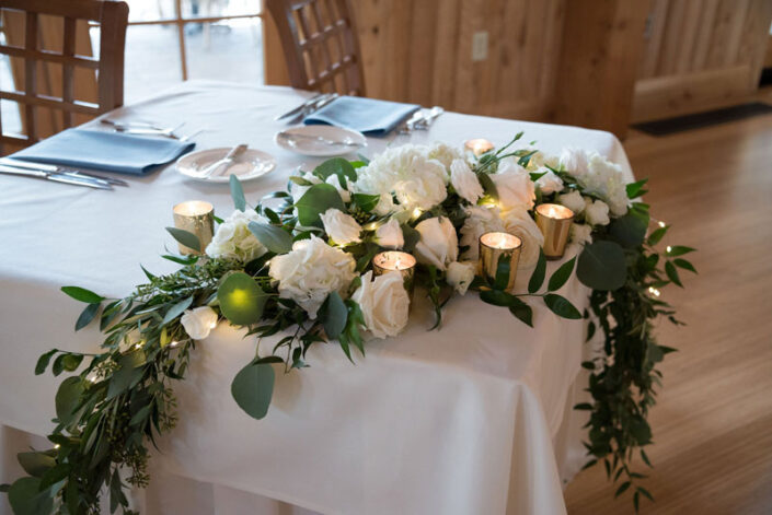 A table with white flowers and candles on it.