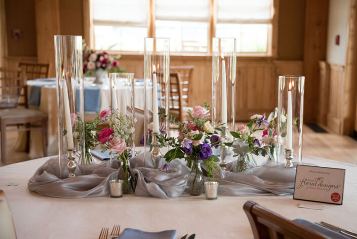 A table with vases and flowers on it.