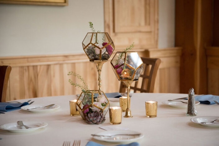 A table setting with gold candle holders and place settings.