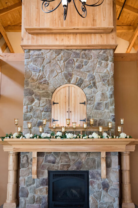 A stone fireplace with candles and a chandelier.