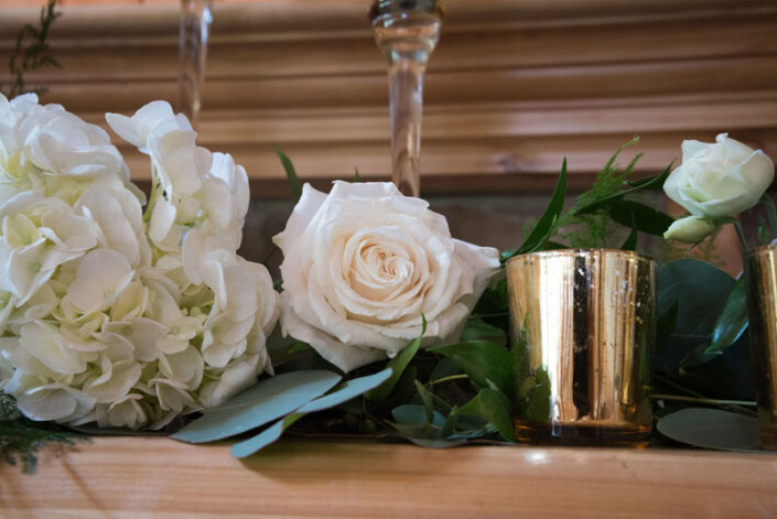 White flowers and gold vases on a mantle.