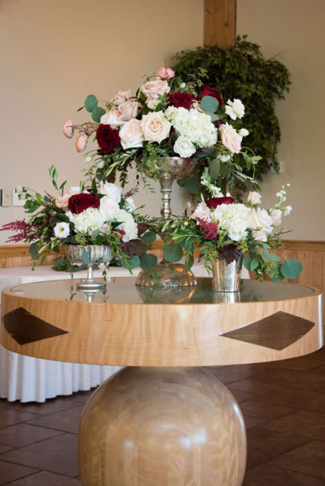 A wooden table with vases of flowers on it.