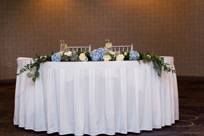 A white table with blue flowers and hydrangeas.