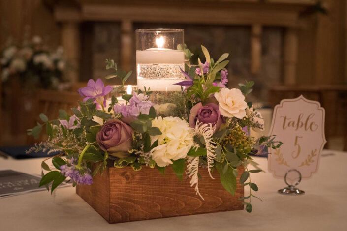 A wooden box with candles and flowers on it.