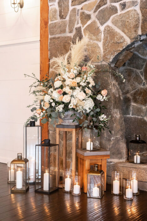 A stone fireplace with candles and flowers in front of it.