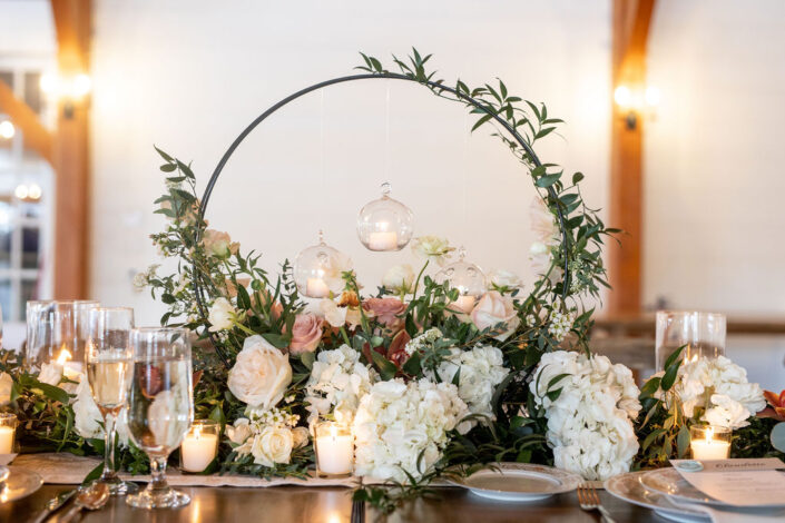 A table with flowers, candles and greenery.