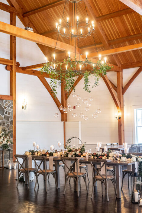 A wedding reception set up in a barn with wooden beams and chandeliers.
