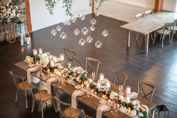 A wedding reception with a long table and hanging lights.