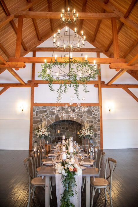 A wedding reception in a barn with wooden beams and a chandelier.