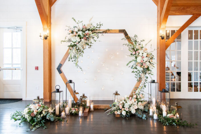 A hexagonal wedding arch with flowers and candles.