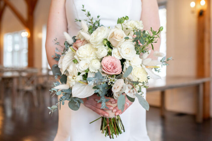 A bride holds a bouquet of white and pink flowers.