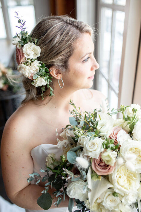 A bride holding a bouquet in front of a window.