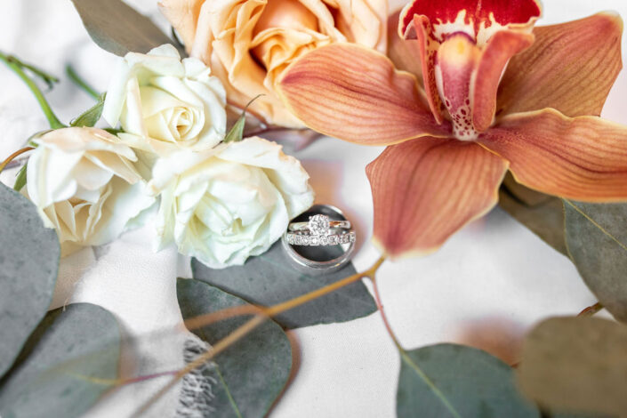 A wedding ring sits on top of a flower.