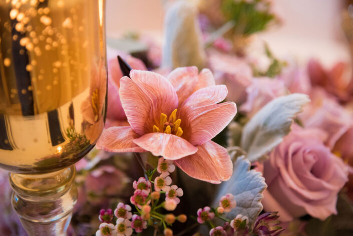 A close up of flowers and a glass of champagne.