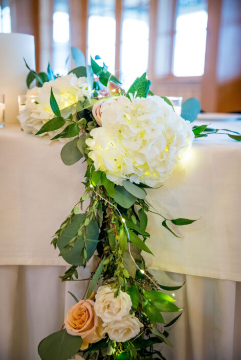 A table decorated with white flowers and greenery.