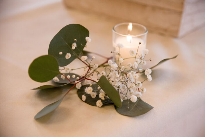 Eucalyptus leaves and a candle on a table.