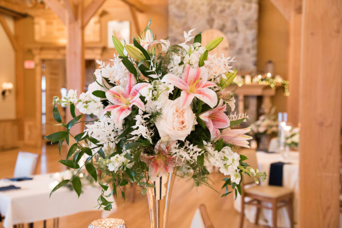 A centerpiece with pink and white flowers on a wooden table.