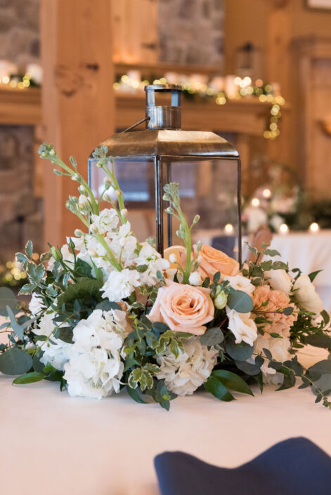A centerpiece with white flowers and greenery on a table.