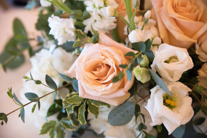 A close up of a bouquet of peach roses and greenery.