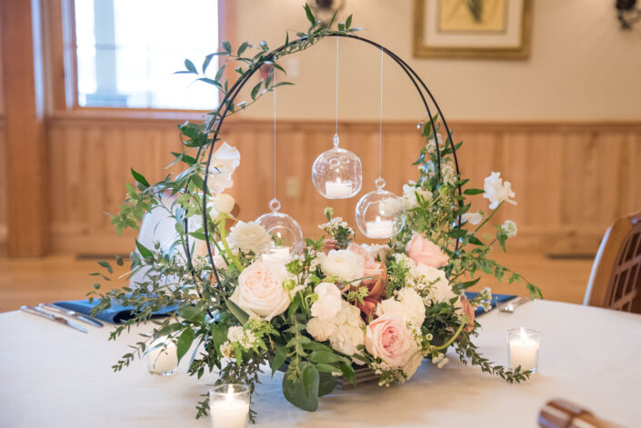 A centerpiece with flowers and candles on a table.