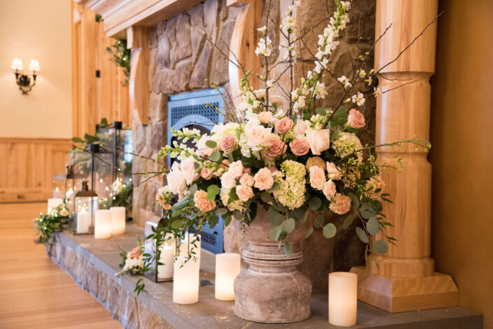 A wedding reception with candles and flowers in front of a fireplace.