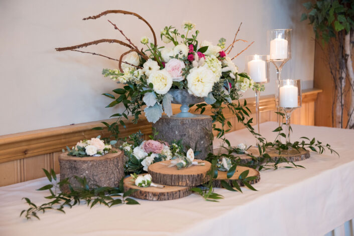 A wooden table with flowers and candles on it.