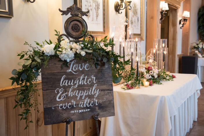 A wooden sign with the words love laughter and happily ever after.