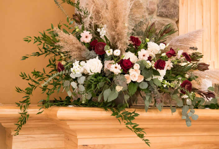 An arrangement of flowers on top of a fireplace mantel.
