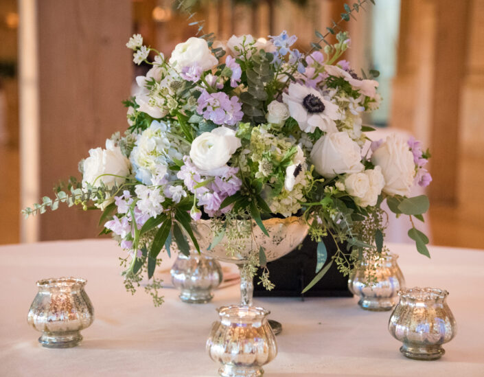 A silver vase with flowers and candles on a table.