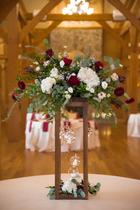 A wooden centerpiece with red, white and green flowers.
