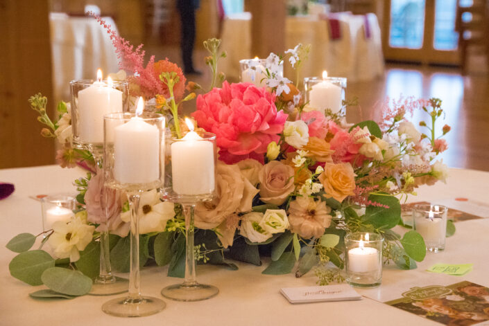 A centerpiece with candles and flowers on a table.