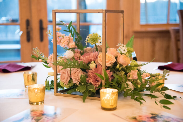A centerpiece with flowers and candles on a table.